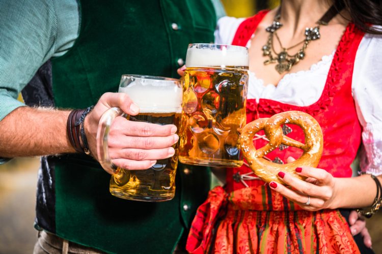 Hands holding Beer and Pretzels, detail of bavarian Tracht